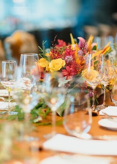 A beautifully set dinner table with numerous glasses, plates, and floral arrangements as a centerpiece, ready for a formal gathering.